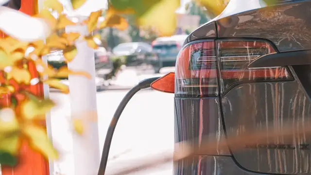 Carro eléctrico conectado a un cargador en la calle